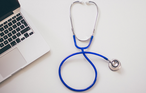 A stethoscope next to a laptop.