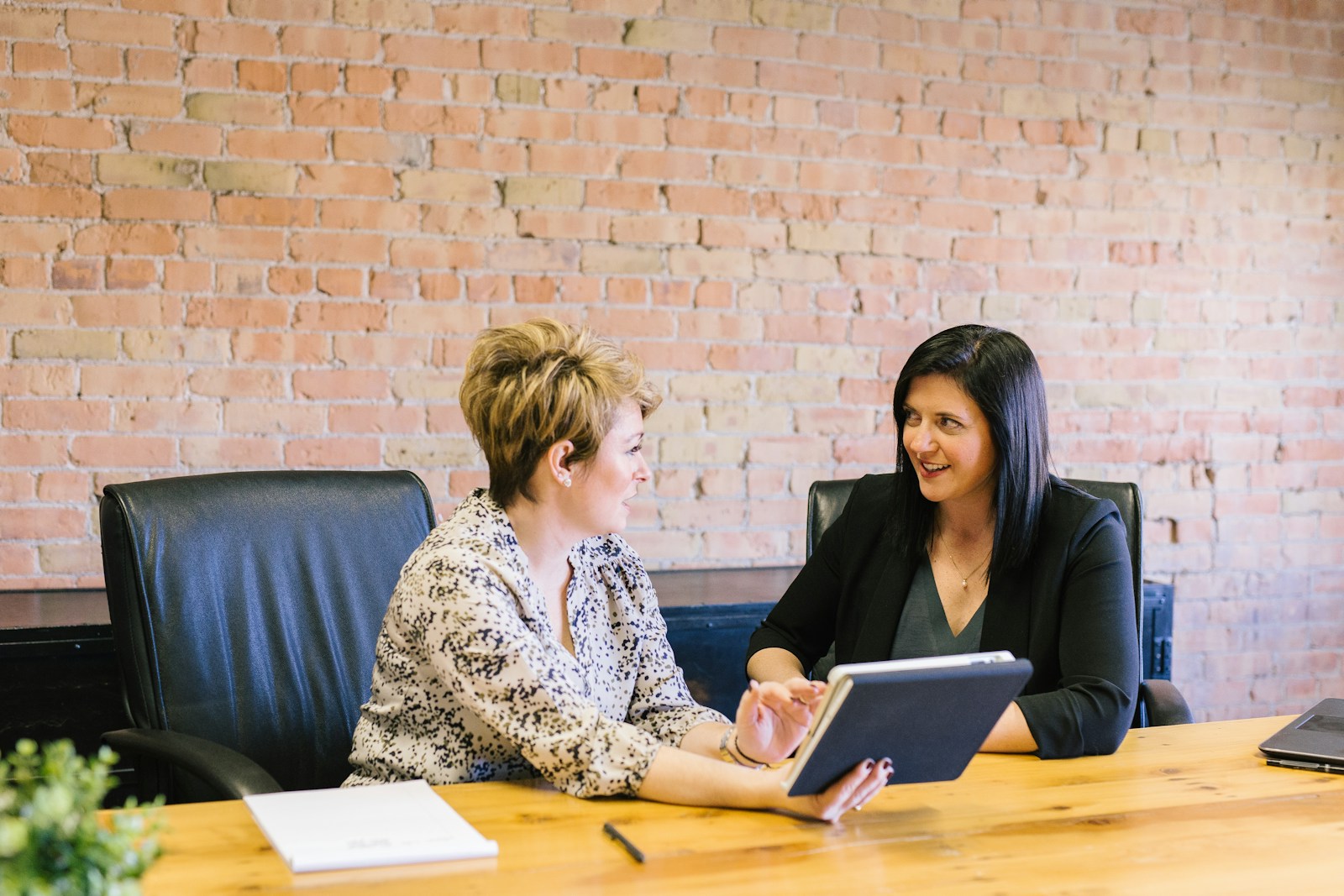 two women sitting on leather chairs in front of table with an Explanation of Benefits and Why it is Important